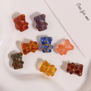 Macro detail of eight colorful bear glass beads with gold line accents on a white tray
