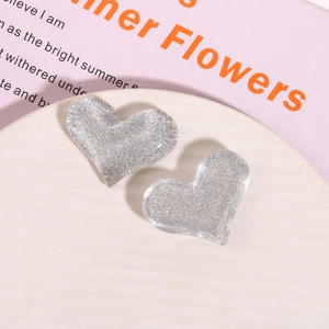 Close-up of heart-shaped glitter resin charms with silver sequins on white tray