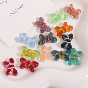 Macro detail of colorful 3D glass bow beads with glitter accents in a heart ceramic dish