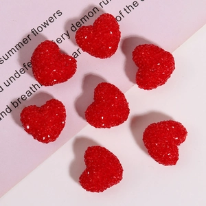 Macro view of red resin heart charms with diamond-cut facets for DIY jewelry making