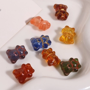Macro detail of colorful glass bear beads with gold glitter lines in a white ceramic dish