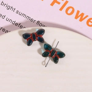 Detailed view of dark blue glass bow charms with red glitter edges for jewelry making