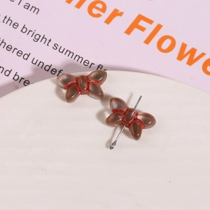 Close-up of translucent brown glass butterfly beads with silver eye pin for DIY jewelry