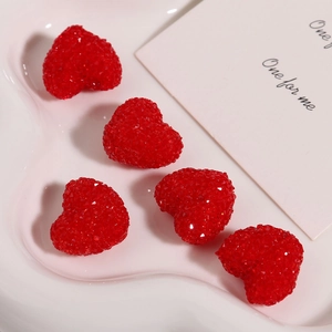 Macro detail of red resin heart charms with faceted crystalline texture in a white tray