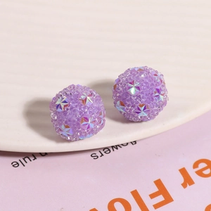 Macro detail of purple shambhala beads with glittery surface and colorful star accents
