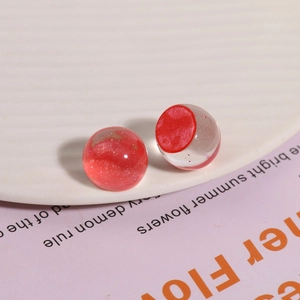 Primer plano de cuentas de resina roja brillantes para joyería DIY en plato blanco
