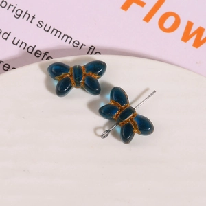 Macro view of blue glass butterfly charms with hand-painted gold edges in ceramic tray