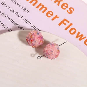 Detail of pink crystal sugar ball resin earrings on a white ceramic display tray