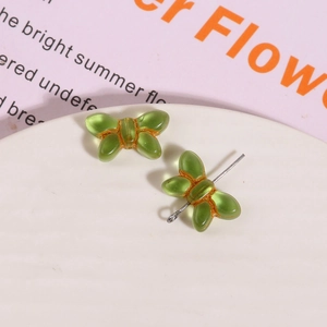Macro view of transparent green glass bow bead with metal rod for DIY jewelry crafting