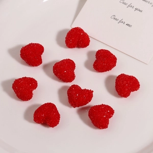 Close-up of nine red sugar-textured resin hearts for DIY crafts on a white ceramic plate