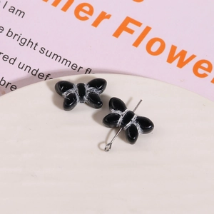 Macro detail of black glass bow beads with metal pins for DIY earring making