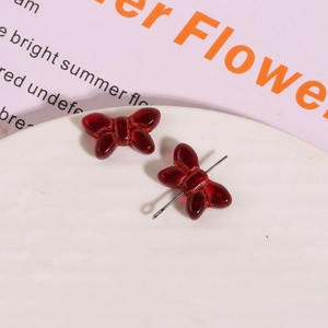 Macro detail of red glass bow-knot charms for DIY jewelry making and earrings