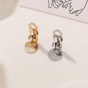 Macro detail of gold and silver DIY ear clip converters on a warm minimalist background