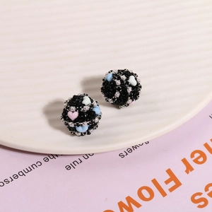 Nahaufnahme schwarzer Strassperlen mit bunten Herzen und weißen Perlen für DIY-Schmuck