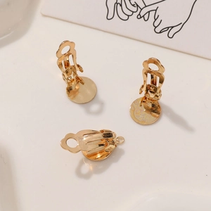 Macro view of three gold-plated clip-on earrings with flat pads for DIY jewelry making