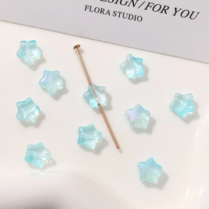 Primer plano de cuentas de vidrio azul claro con forma de estrella y acabado iridiscente DIY