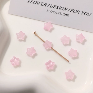 Detalle macro de cuentas de vidrio estrella rosa 8mm con pin dorado para joyería DIY