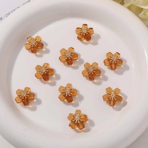 Close-up of translucent amber resin cherry blossom charms with gold stamen centers