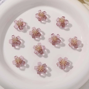 Close-up of 11 purple resin flower charms with gold metal centers for DIY jewelry making