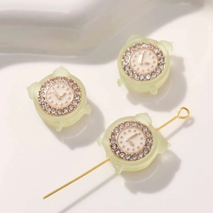 Makroansicht der mattgrünen Wecker-Anhänger mit glitzernden Strasssteinen für DIY-Schmuck