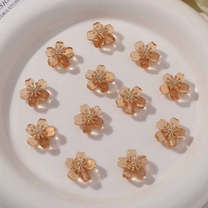 Close-up of translucent amber resin flower charms with golden stamens in a white ceramic bowl
