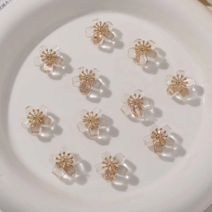 Macro detail of transparent resin flower beads with gold centers on a white ceramic plate