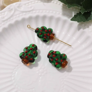 Detailed view of handmade green glass Christmas tree beads with festive red dots for DIY jewelry