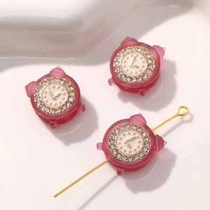 Makroaufnahme: Roter mattierter Wecker-Anhänger mit Strasssteinen für DIY-Schmuck