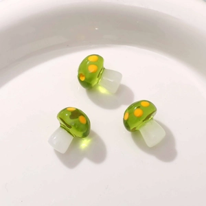 Macro detail of three semi-transparent resin mushroom charms with green dots for DIY jewelry