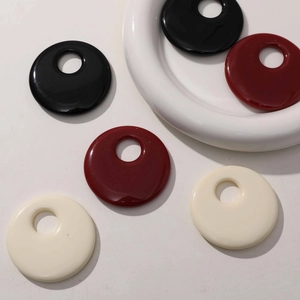 Close-up of 50mm hollow resin discs in black, burgundy and cream for DIY jewelry making