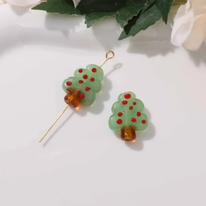 Detailed view of handmade glass Christmas tree beads for DIY jewelry with green and red accents