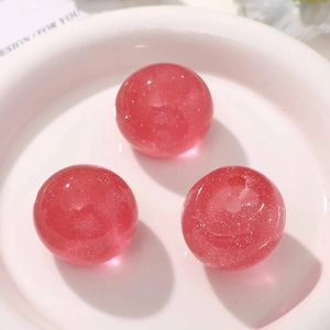Macro shot of three pink glitter resin round beads for DIY jewelry and keychain making