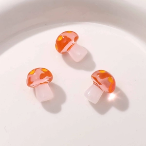 Macro shot of three glossy resin mushroom charms with red dotted caps for DIY jewelry