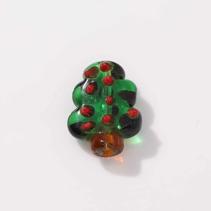 Close-up of green glass Christmas tree bead with red dots and brown base for DIY jewelry