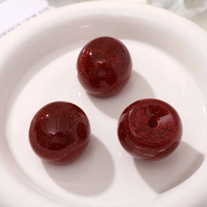 Macro detail of red glitter resin cherry beads with drill holes for DIY jewelry making
