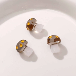 Macro detail of three semi-transparent resin mushroom charms with yellow polka dots