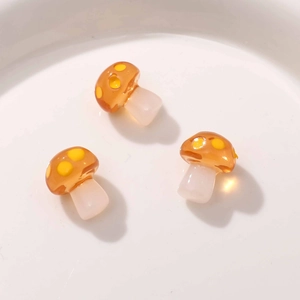 Close-up of three orange resin mushroom charms with yellow polka dots for DIY jewelry