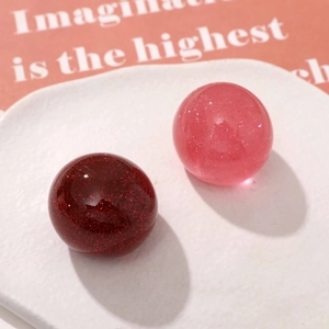 Macro shot of glittery resin cherry charms in red and pink for DIY keychain making