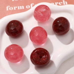 Close-up of sparkling cherry-shaped resin beads in red and pink for DIY jewelry making