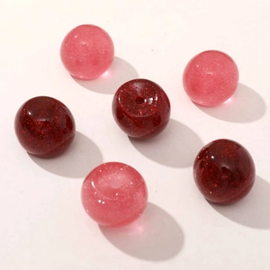 Close-up of cherry red and pink glitter resin beads with central holes for DIY jewelry