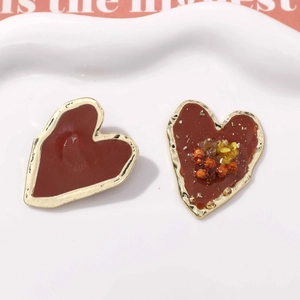 Detail von asymmetrischen Herzohrringen mit roter Emaille und Goldfolien-Inlay