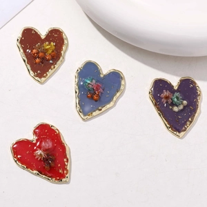 Detailansicht herzförmiger Legierungsanhänger mit Emaille, Trockenblumen und Wellenkanten