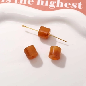 Macro shot of amber resin cylinder beads and golden pin accessories for DIY earrings