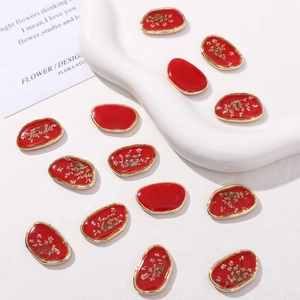 Dettaglio di ciondoli ovali in resina rossa con bordi dorati e veri fiori secchi per gioielli