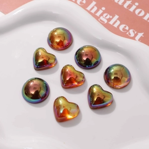 Iridescent geometric heart and round resin charms in a decorative white dish