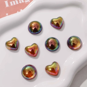 Iridescent geometric heart and round resin charms on white tray for DIY crafts