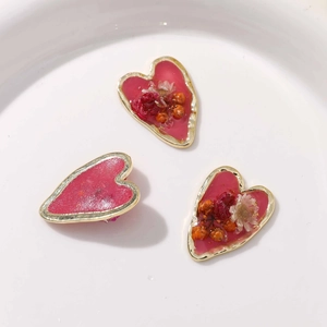 Détail macro de pendentifs cœurs en résine avec fleurs séchées et bords en alliage