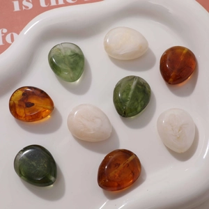 Flat round drop beads in amber and marble patterns for DIY jewelry making in ceramic bowl