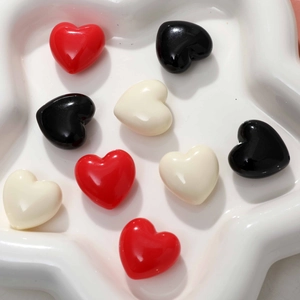 Pendentifs cœur en résine polie rouge, noir et blanc sur un plateau blanc décoratif