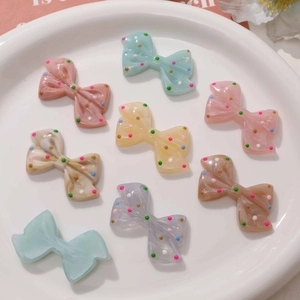 Colorful polka dot resin bows in macaron colors displayed on a white ceramic tray